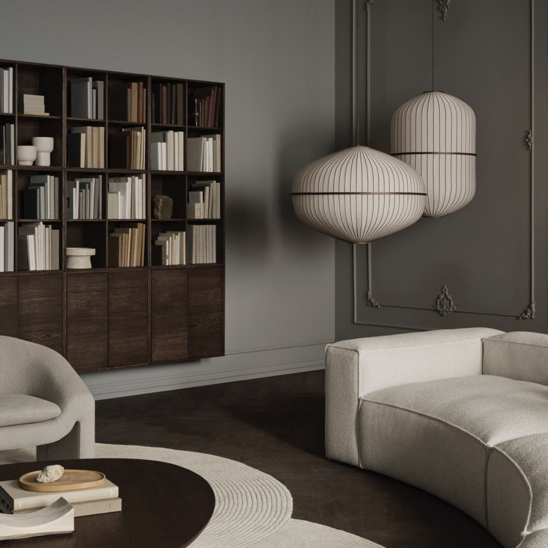 Textured beige sofa and round rug against a dark wood floor; modern light fixtures with cream and brown stripes.