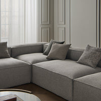 Gray sectional sofa with textured fabric and matching throw pillows, set against a neutral backdrop for a modern look.