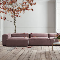"Modern oversized sofa in soft mauve fabric, featuring clean lines and minimalistic design, set on a rustic wood floor."