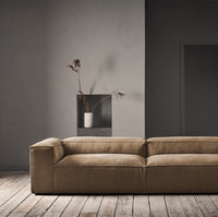 Sleek tan sofa with a subtle texture, complementing minimalist gray walls and wooden flooring for a modern look.