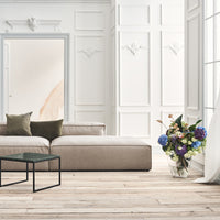 Beige sectional sofa with olive green and cream cushions, paired with a colorful floral arrangement in a bright, airy space.