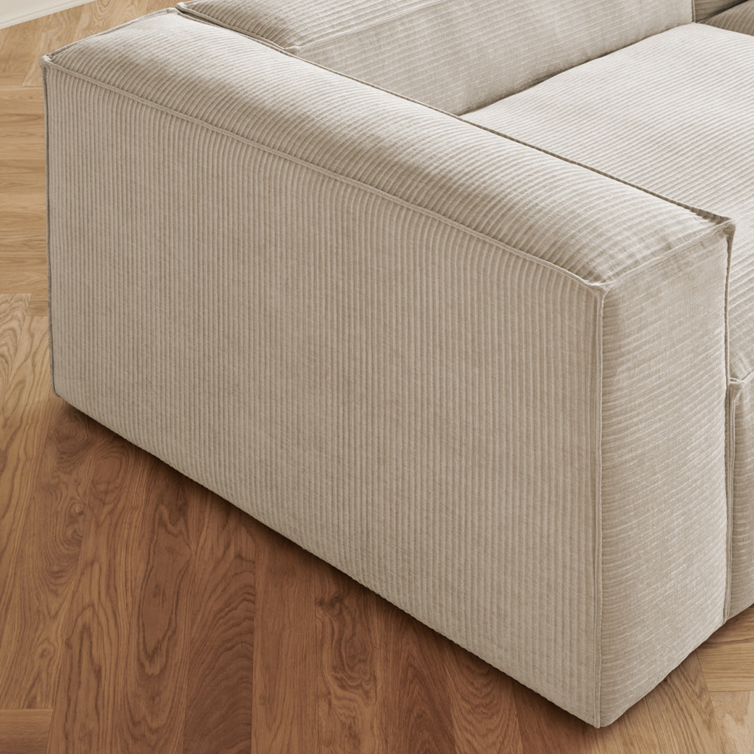 Beige ribbed fabric upholstery on a modern sofa, complemented by a warm wooden floor.