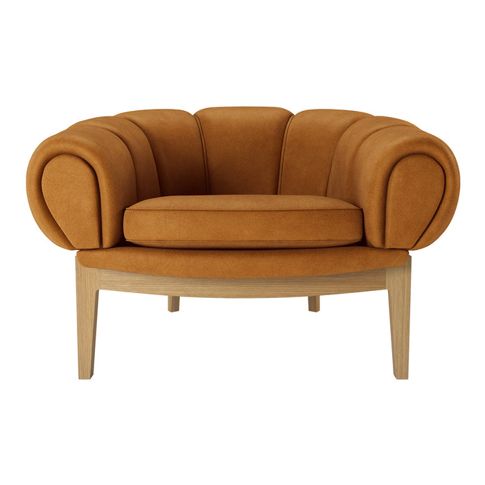 Orange velvet armchair with rounded design and wooden legs, perfect for adding a pop of color to any space.