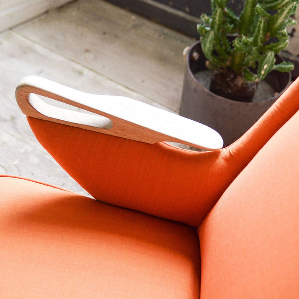 "Close-up of vibrant orange chair with sleek wooden armrest and subtle texture, perfect for modern interiors."