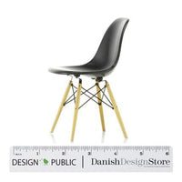 Black molded plastic chair with light wooden legs and a minimalist design, featuring a sleek, modern silhouette.