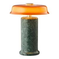 Orange glass lampshade on a green marble base, featuring smooth textures and bold color contrast.