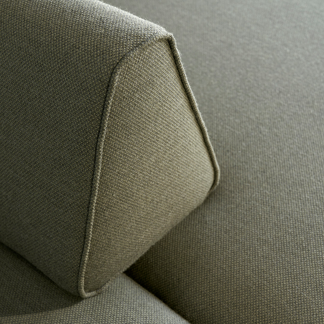Close-up of soft, textured green upholstery with a subtle angular design and contrasting stitching.