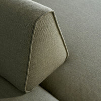 Close-up of soft, textured green upholstery with a subtle angular design and contrasting stitching.