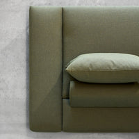 Olive green upholstered headboard with smooth, minimalistic design and matching accent pillow. Modern texture and style.