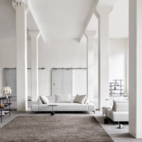 Modern living room with neutral tones, soft gray upholstery, and a textured brown rug, complemented by minimalist decor.