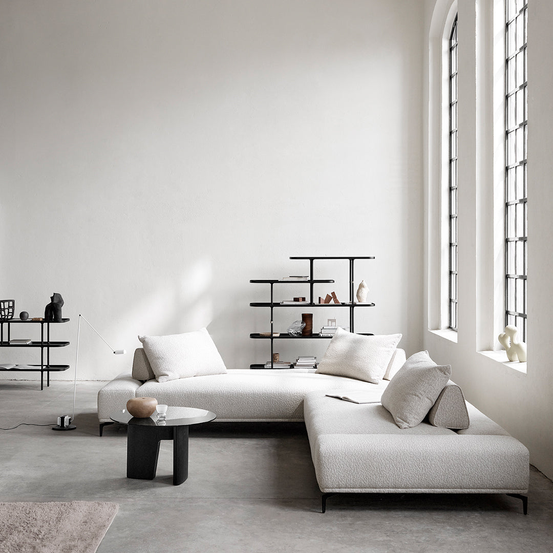 Light beige sectional sofa with subtle textured cushions, complemented by a minimalist black coffee table in a bright, airy room.