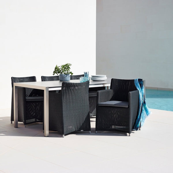 Black woven dining set with a sleek silver table, accented by blue and green decor against a light backdrop.