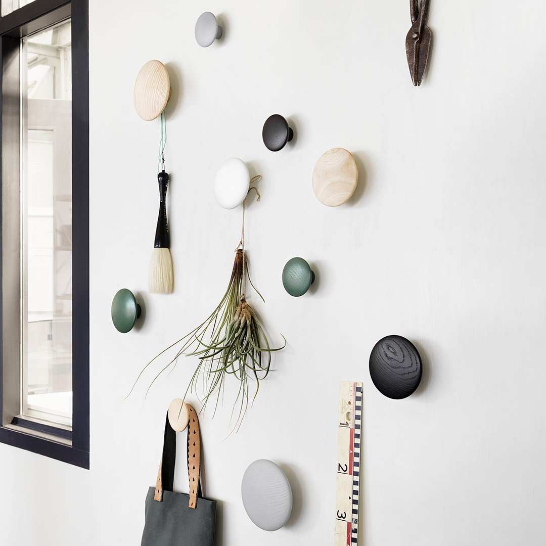 Colorful wall hooks featuring wood, black, white, green, and gray finishes in a modern, minimalist arrangement.