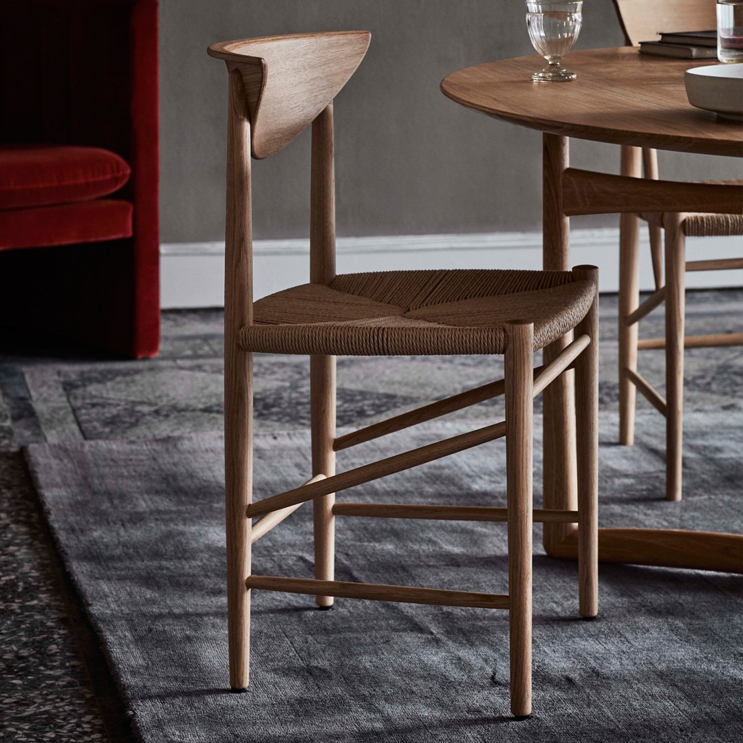 Natural wood chair with woven seat, featuring a light oak finish and minimalistic design against a textured gray background.