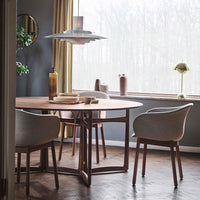 Modern dining room featuring a round wooden table and soft gray chairs, set against muted walls and natural light.