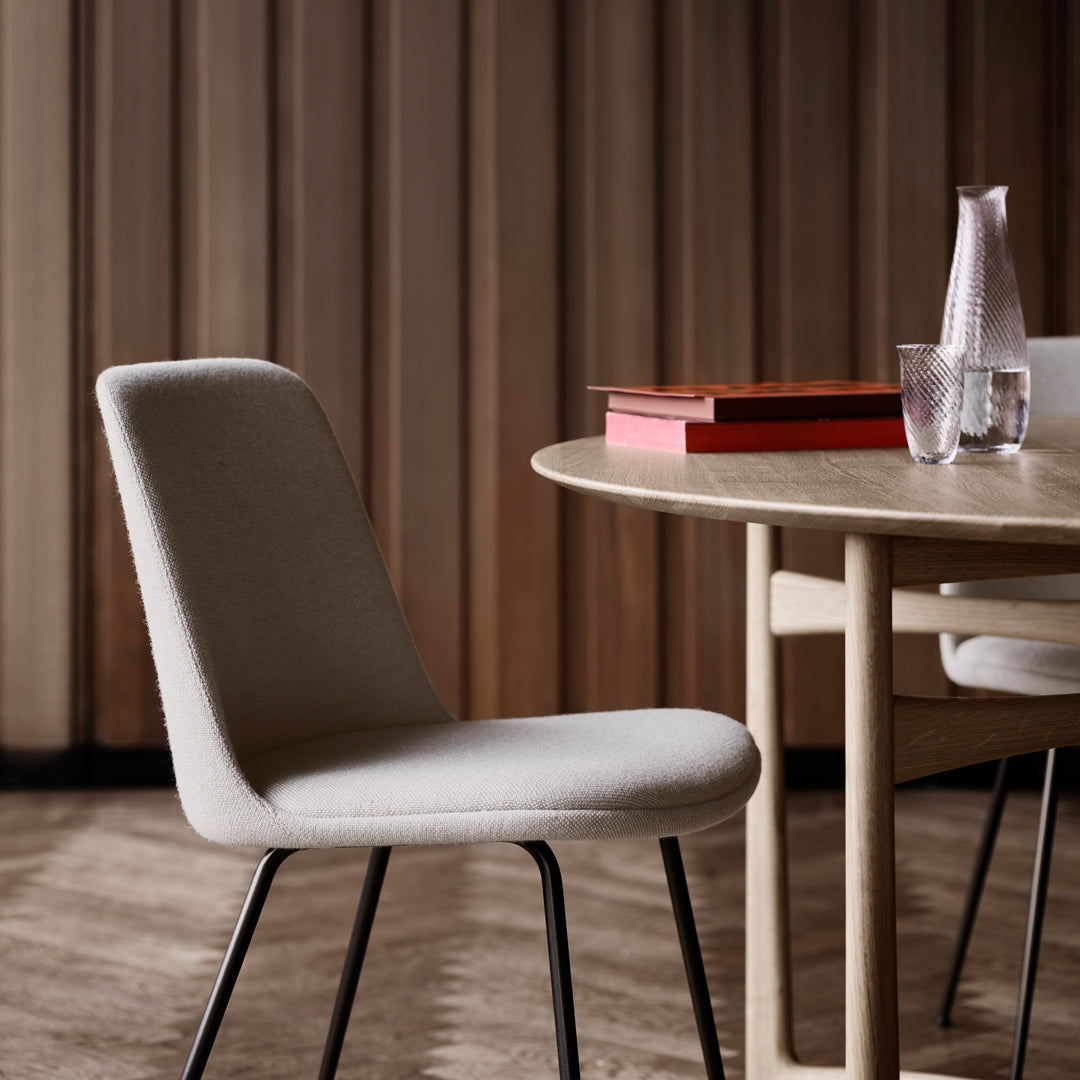 Neutral beige chair with a smooth fabric texture, set against a warm wooden backdrop and minimalistic design elements.