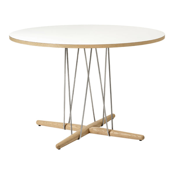 Round white tabletop with natural wood base and sleek silver supports, creating a modern minimalist design.