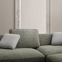 Textured green sofa with gray accent pillows, featuring a modern, minimalist pattern against a neutral backdrop.