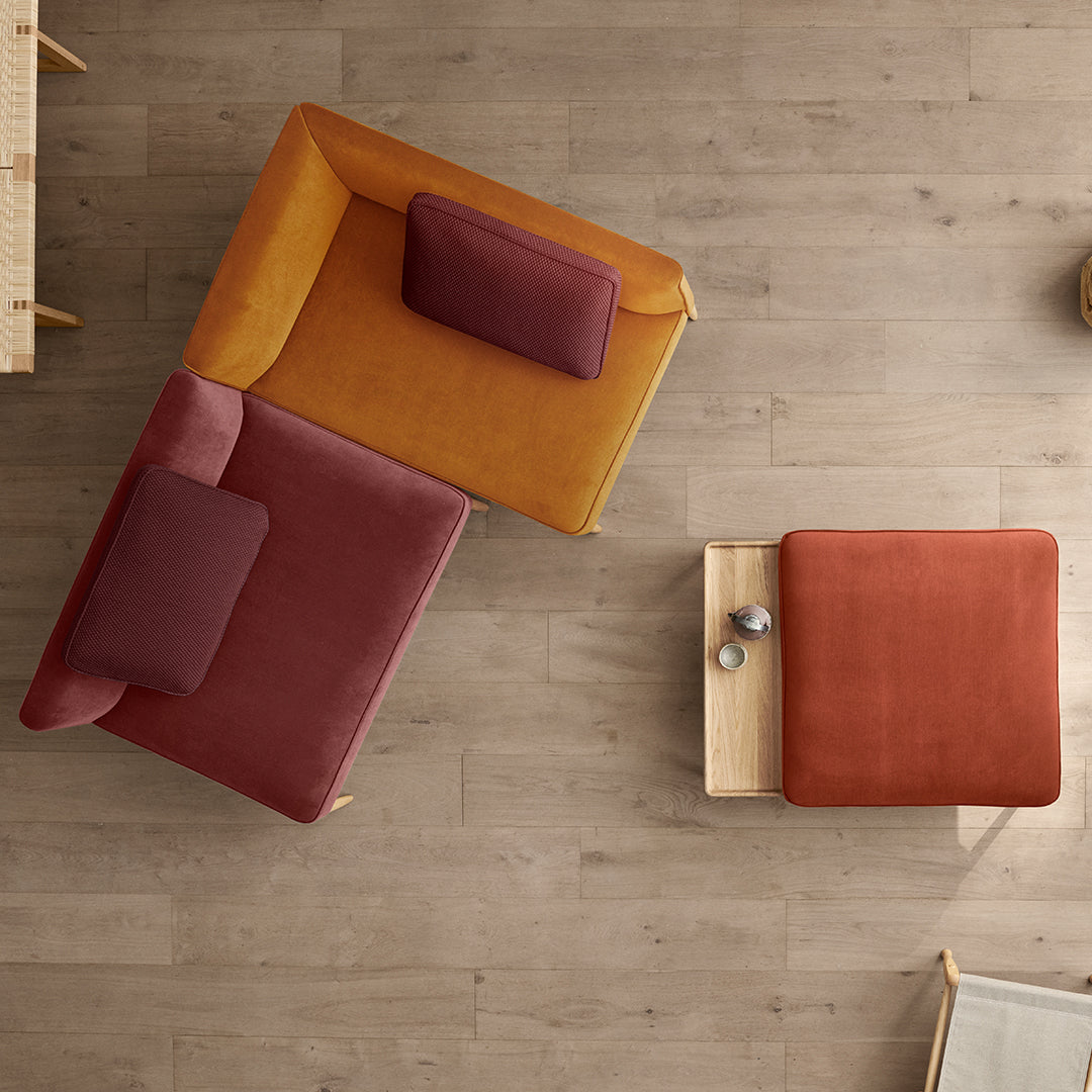 "Modern seating in mustard yellow and rich burgundy, with a complementary terracotta accent table on light wood floor."