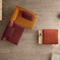 "Modern seating in mustard yellow and rich burgundy, with a complementary terracotta accent table on light wood floor."