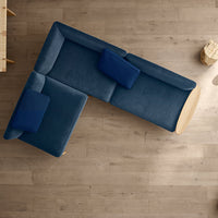 L-shaped sectional sofa in deep navy blue with matching cushions, set atop light wooden flooring.