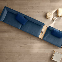 Top view of a sleek navy blue sectional sofa with soft upholstery and light wood accents on the side table.