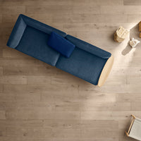Navy blue fabric sofa with a contrasting light wood base and a darker blue accent pillow, simple and modern design.