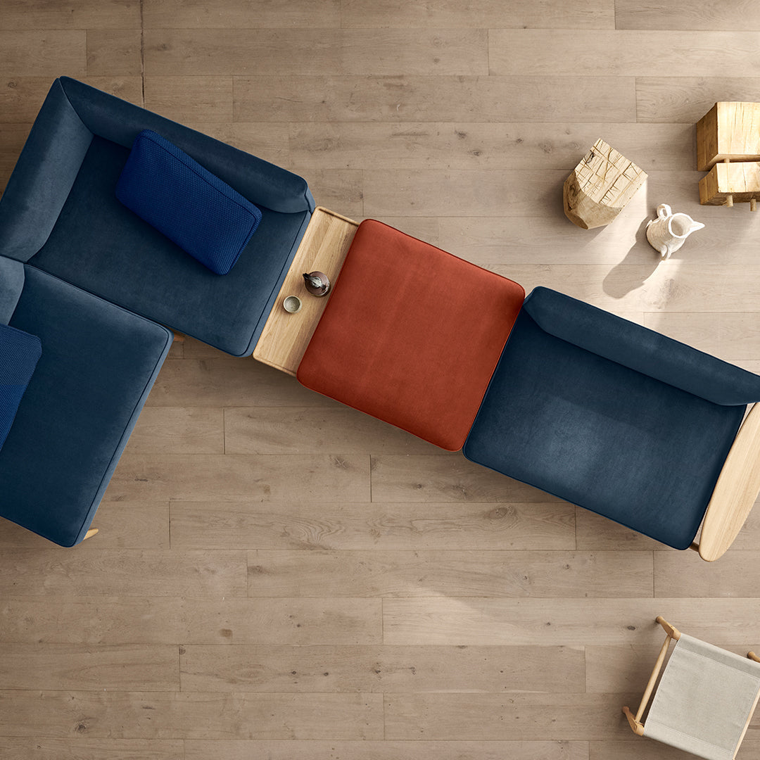 Modern sectional sofa with deep blue and rust orange cushions, featuring a sleek wood accent in a stylish arrangement.