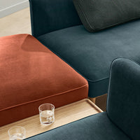 Teal and burnt orange sofa cushions with textured patterns, complemented by a wooden table and glasses.