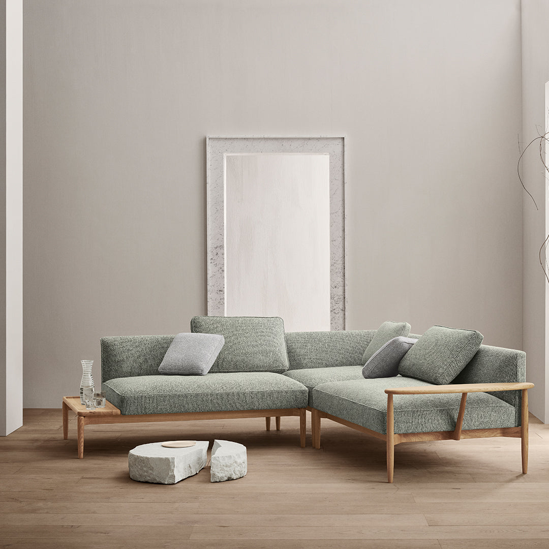Modern light green sectional sofa with a textured fabric and natural wood legs, complemented by light gray cushions.
