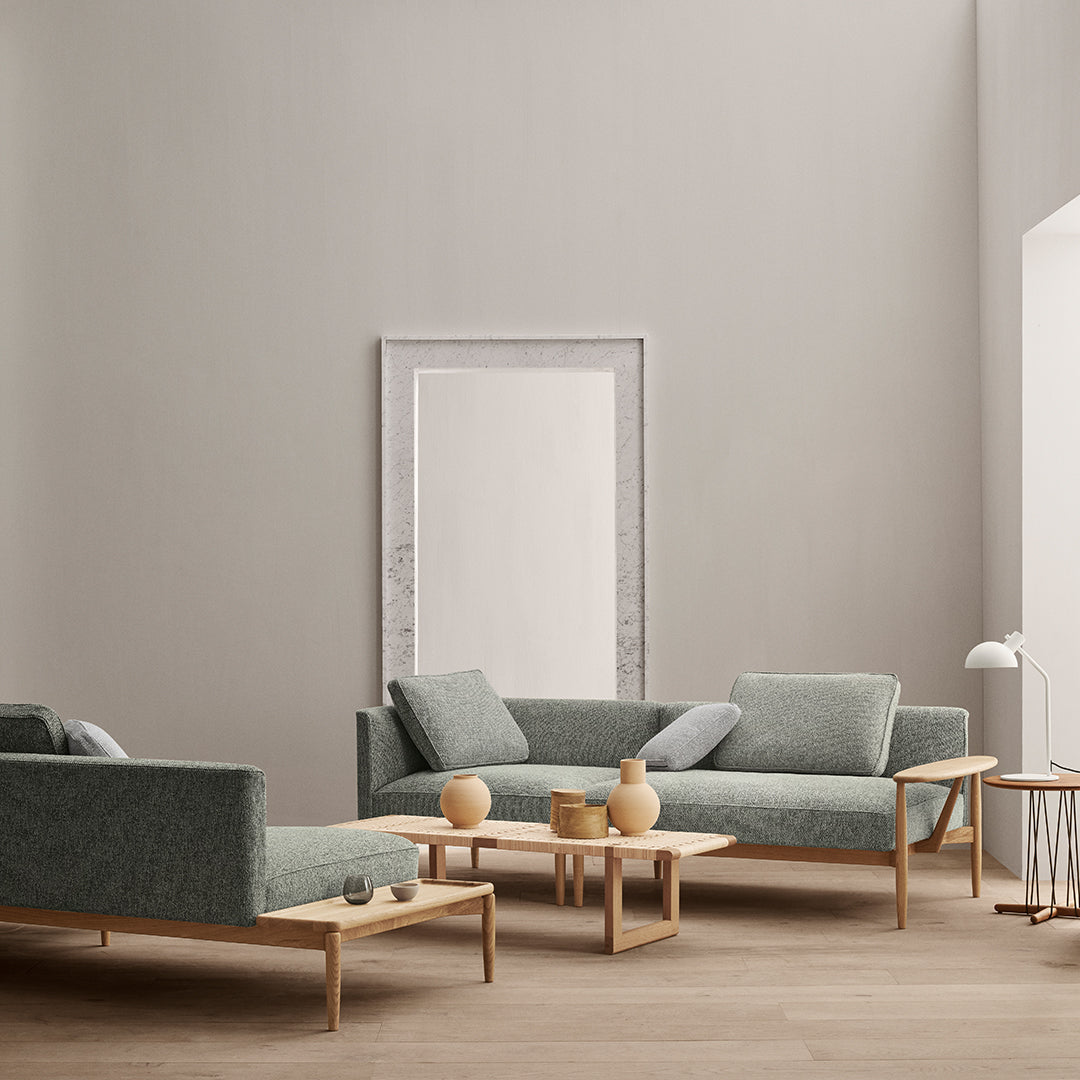Modern green fabric sofa set with minimalist wooden frames and soft blue accents against a neutral wall.