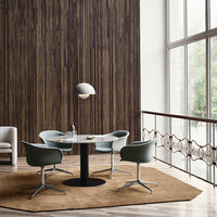 Elegant round table with four blue-green chairs on a soft brown rug, set against a textured wooden wall.