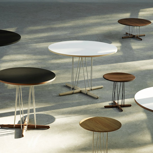 Modern tables in black, white, and warm wood tones with sleek, minimalist designs and varying heights.