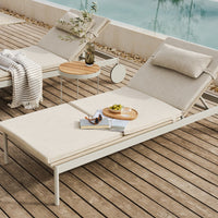 Neutral beige lounge chair with subtle texture, paired with light wood accents and a cozy striped throw.