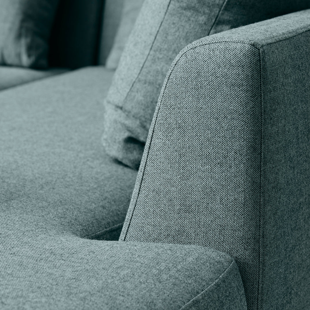 Close-up of a textured teal sofa fabric with a subtle heather pattern and clean, modern lines.