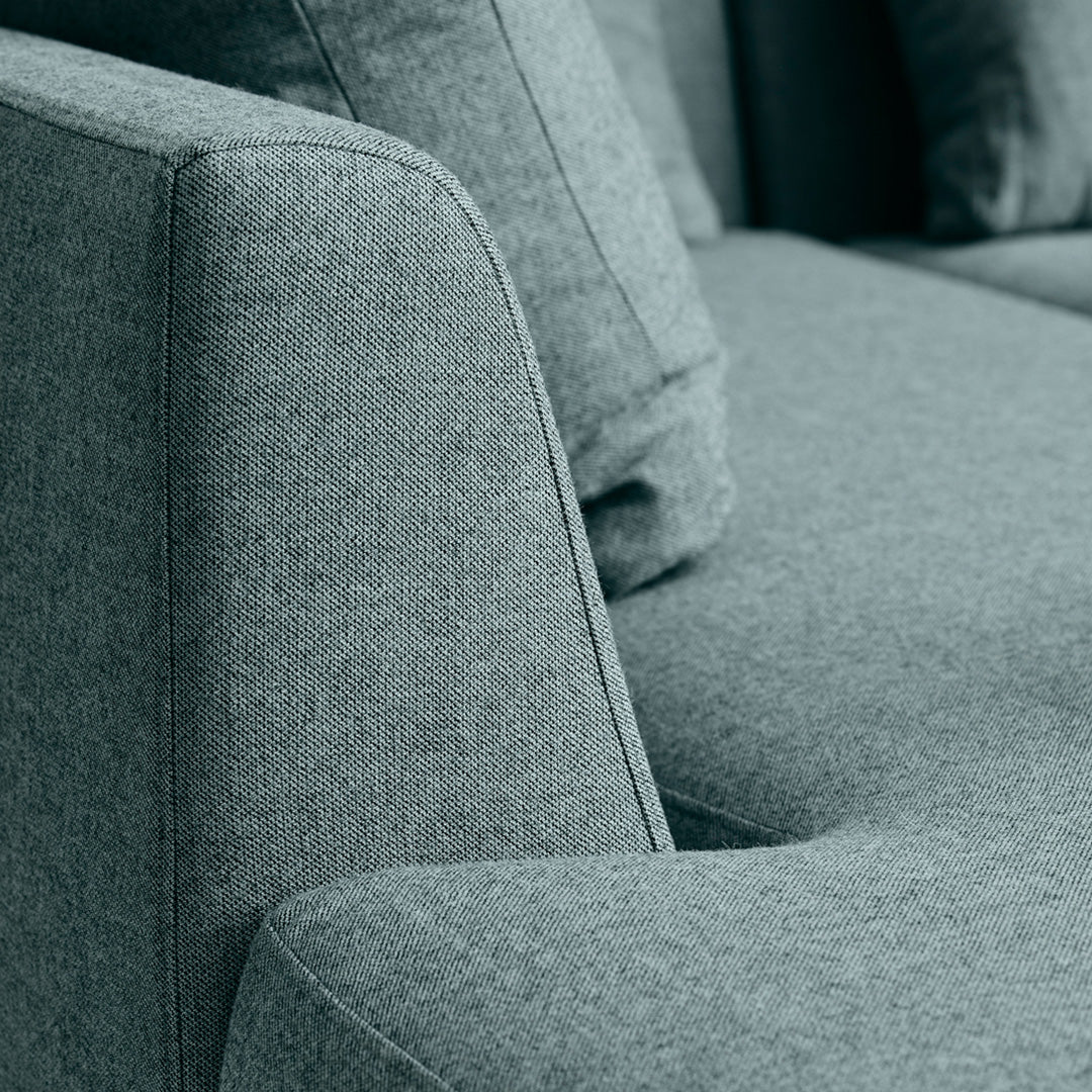 Soft gray upholstered couch with a textured, minimalist design and plush cushions.