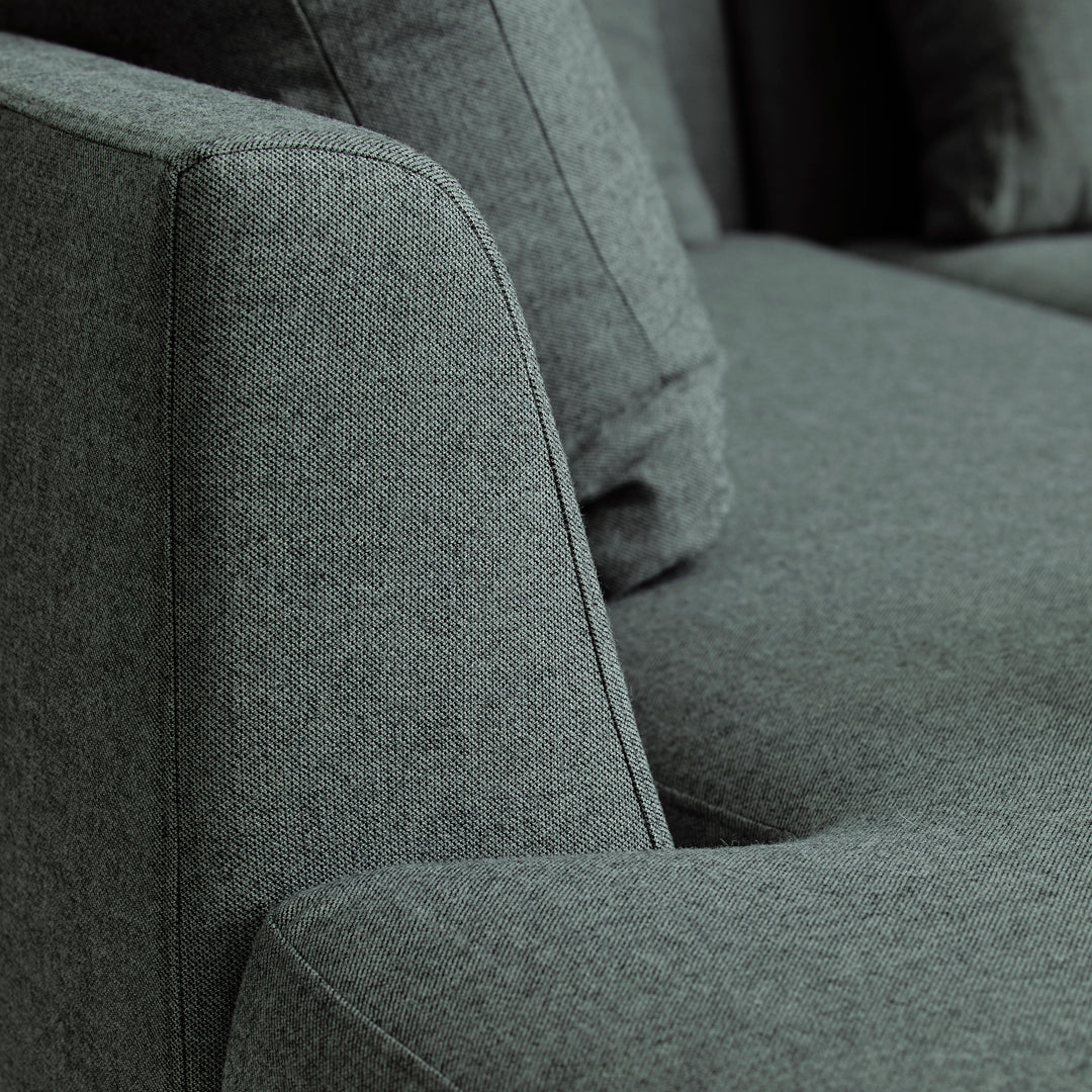 "Close-up of a modern gray upholstered sofa with a textured fabric and sleek armrest design."