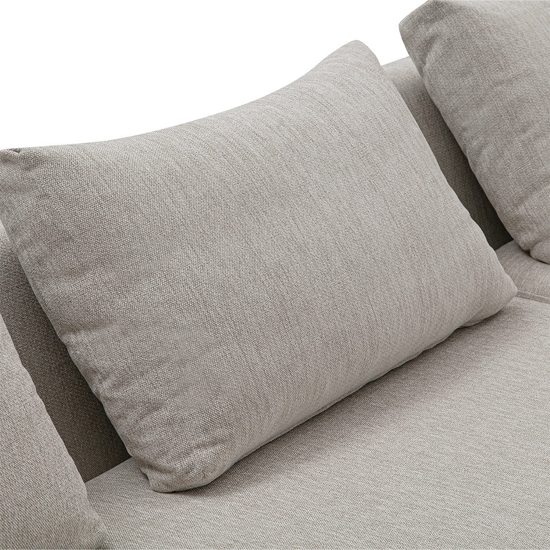 Light beige throw pillow with subtle texture, complementing a soft gray sofa fabric. Cozy modern decor accent.