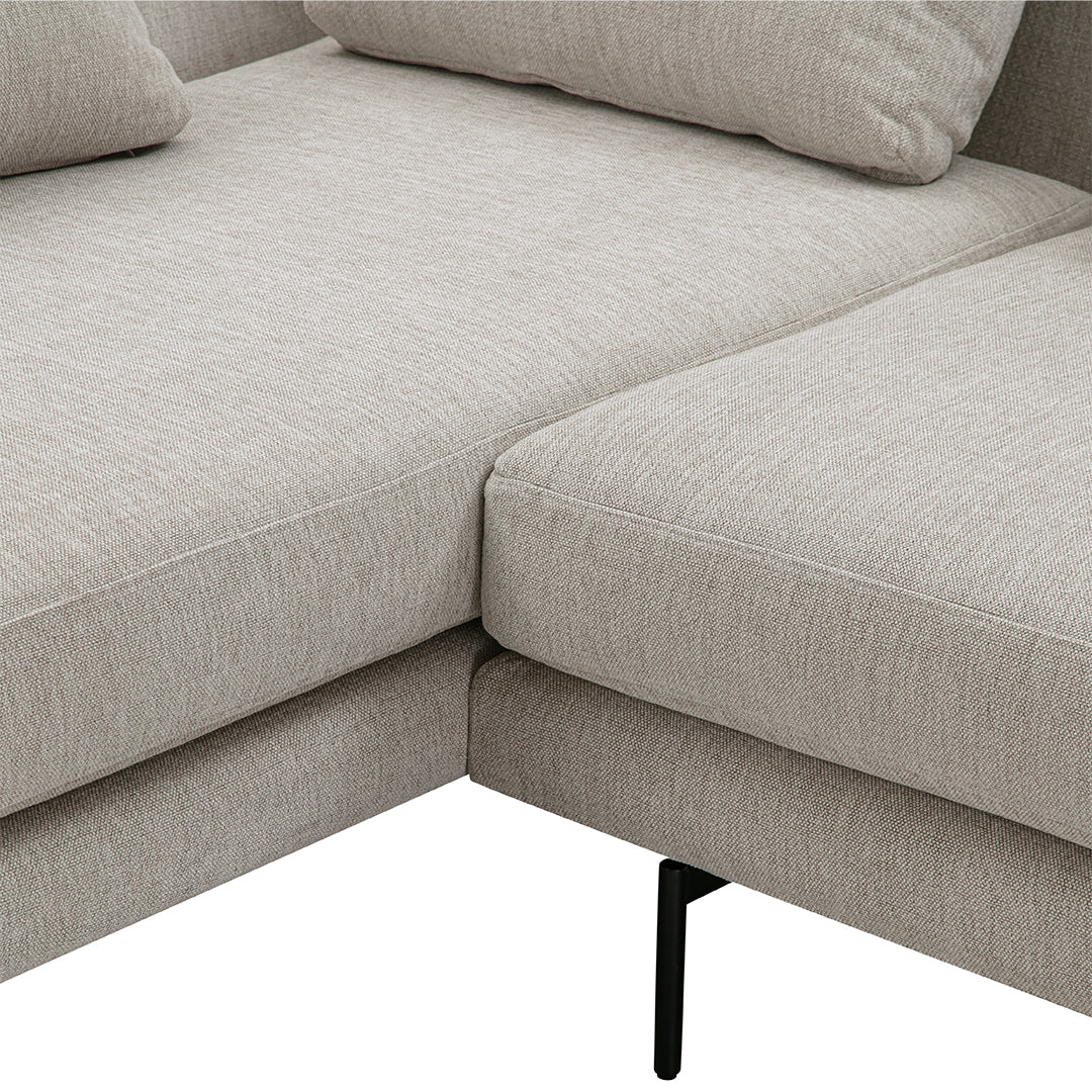 Light beige sectional sofa with subtle textured pattern and sleek black legs, perfect for modern living spaces.