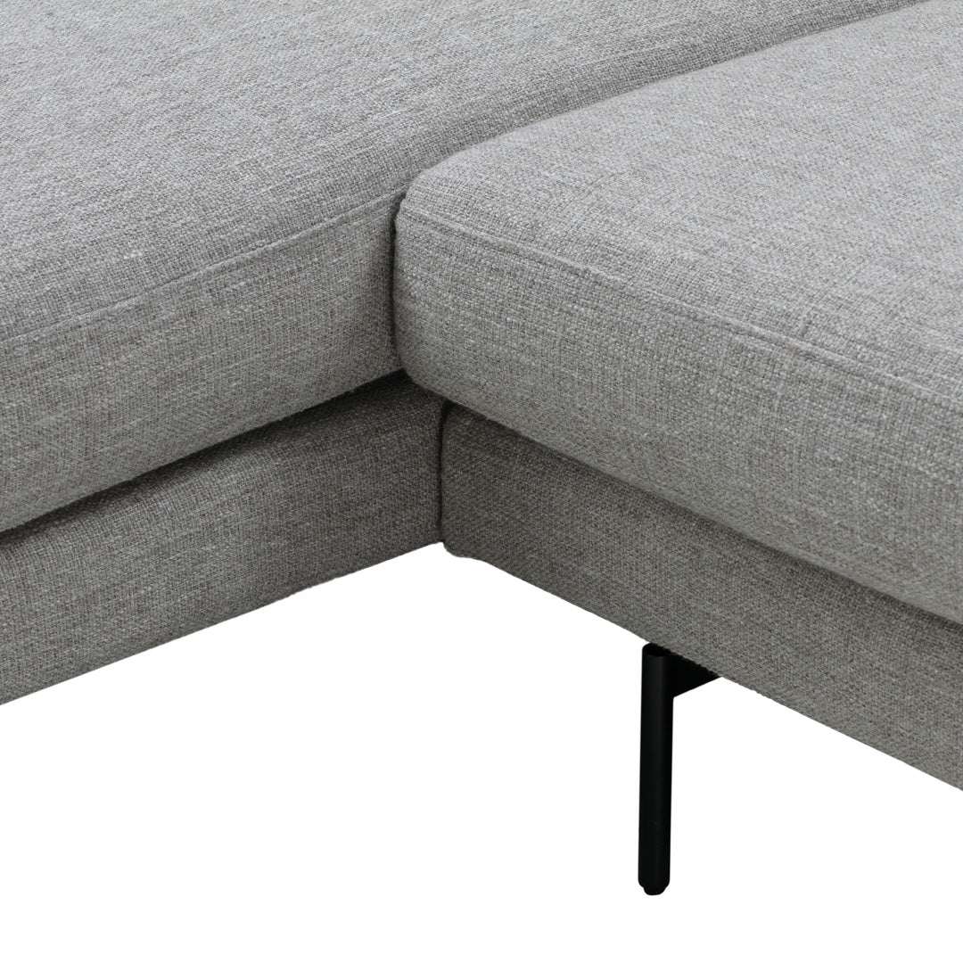 Gray upholstered sectional sofa with a textured fabric and sleek black metal legs. Minimalist and modern design.