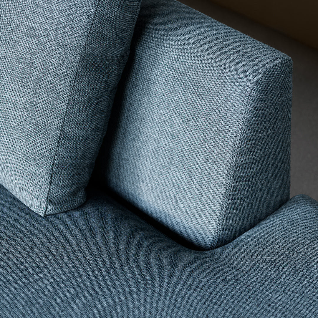 Blue textured fabric sofa with contrasting smooth cushion, featuring a modern, minimalist design.