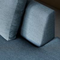 Blue textured fabric sofa with contrasting smooth cushion, featuring a modern, minimalist design.