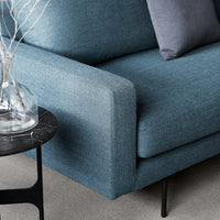 Modern blue sofa with a textured fabric, complemented by a gray throw pillow and a sleek black side table.