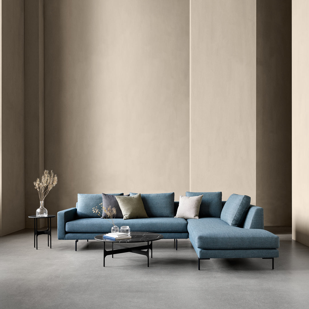 Modern blue sectional sofa with solid fabric and subtle textured cushions, set against a muted beige wall.