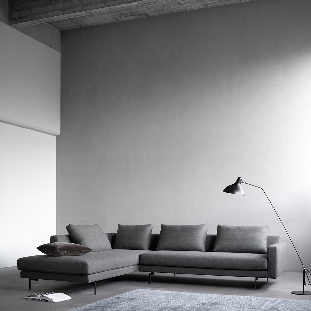Gray sectional sofa with sleek lines, complementing soft gray wall and textured rug for a modern, minimalist look.