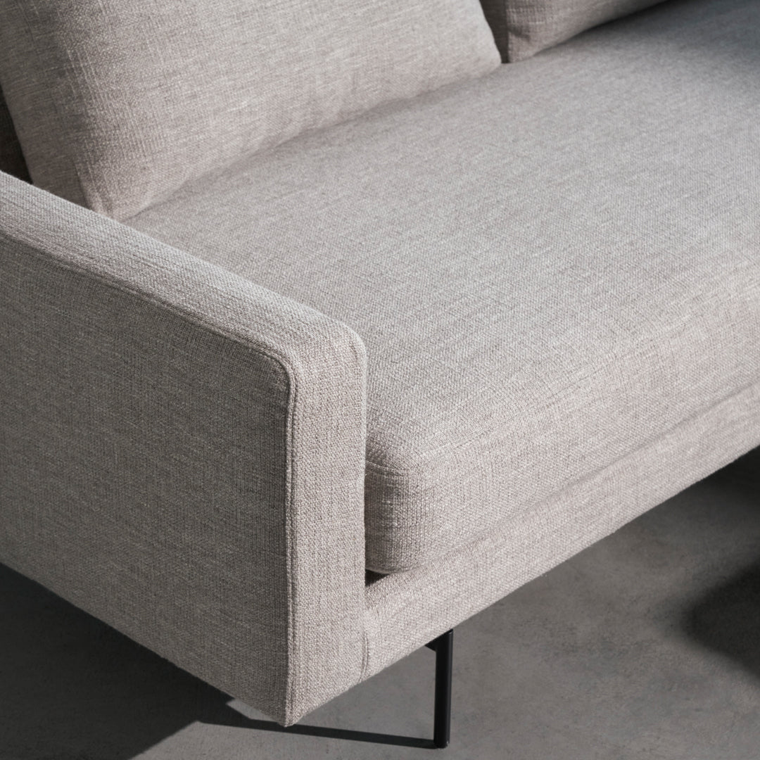 Light gray sofa with a subtle textured pattern and clean lines, complemented by a sleek black metal base.