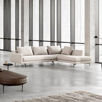 Neutral beige sectional sofa with smooth fabric and minimalist design, complemented by a soft area rug and sleek furnishings.