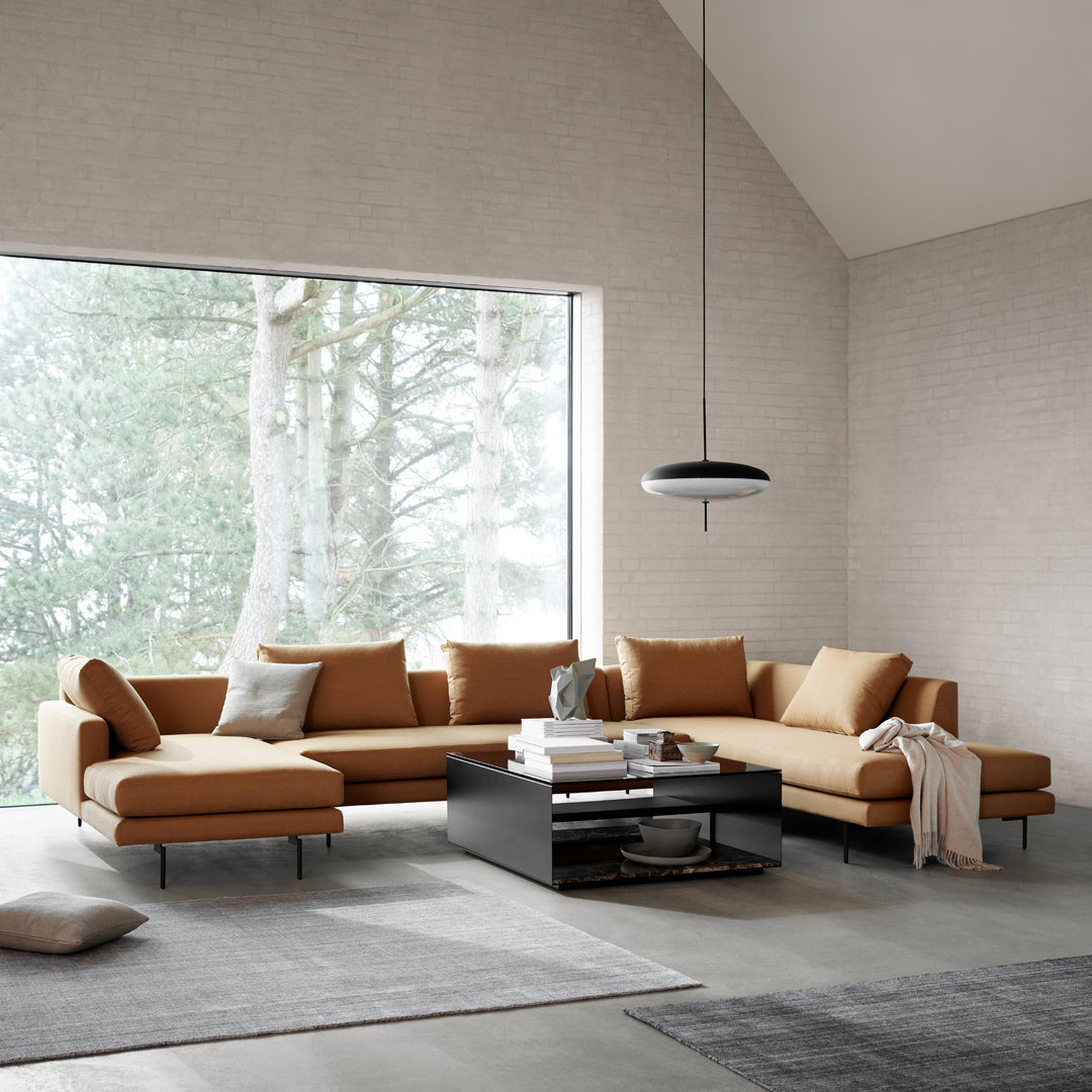 Modern L-shaped sofa in warm caramel hue with smooth fabric, paired with dark wood accents and light gray textiles.