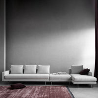 Light gray sectional sofa with smooth cushions, complemented by a textured burgundy accent rug.