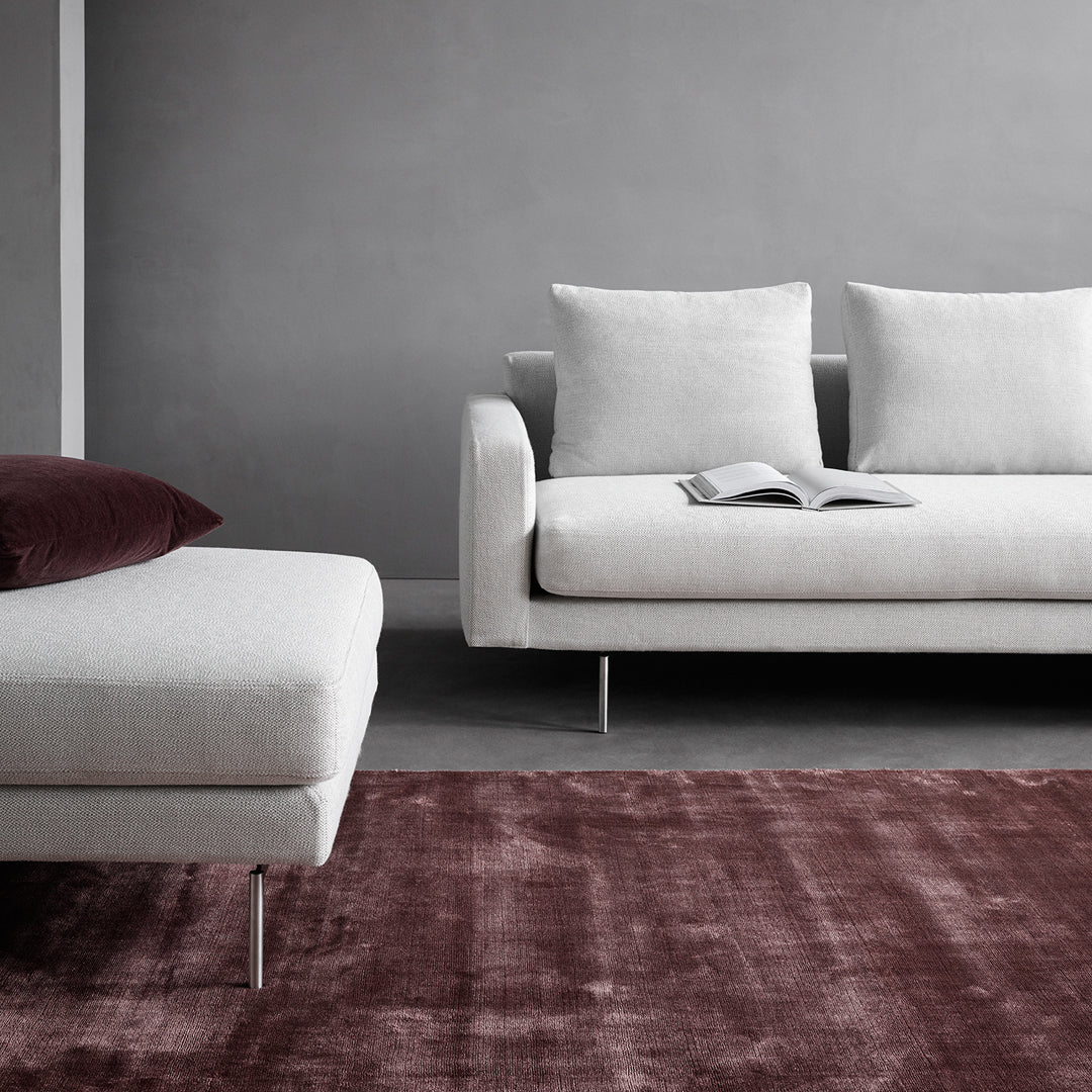 Modern grey sofa with white cushions and a deep burgundy rug, creating a chic, contemporary living space.